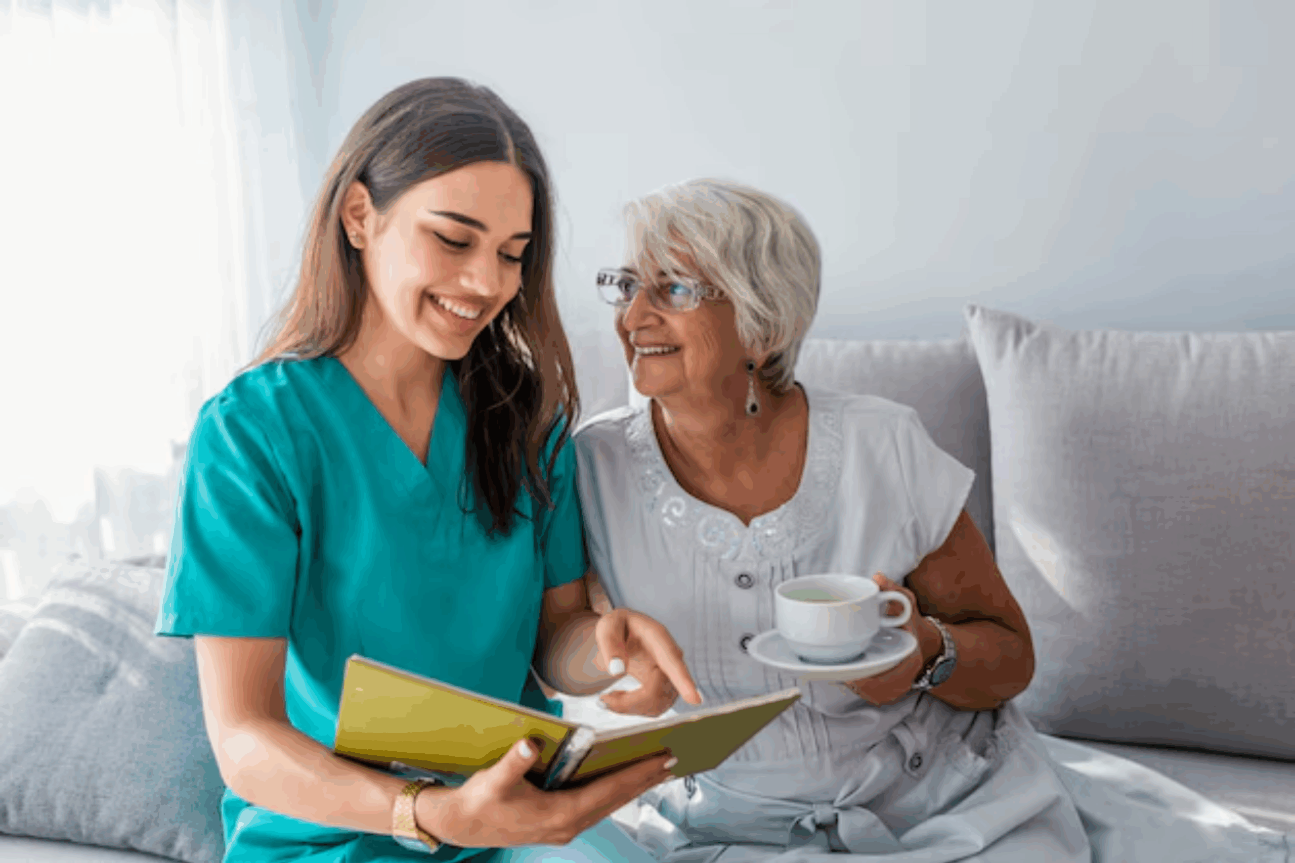 Smiling caregiver showing a book to an elderly woman, highlighting compassionate home care in San Francisco